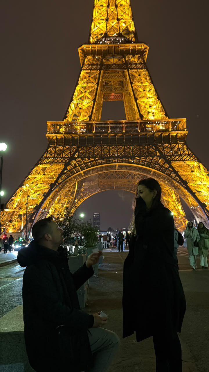 Gustavo pedindo Gabriella em casamento em frente à Torre Eiffel iluminada.