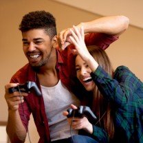 Casal se divertindo com controles de videogame.